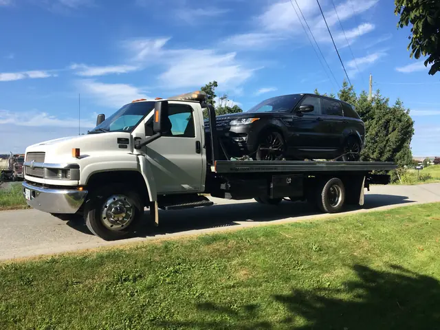 Black Range Rover SUV loaded on a Cash for Cars BC flat deck on a Lower Mainland street