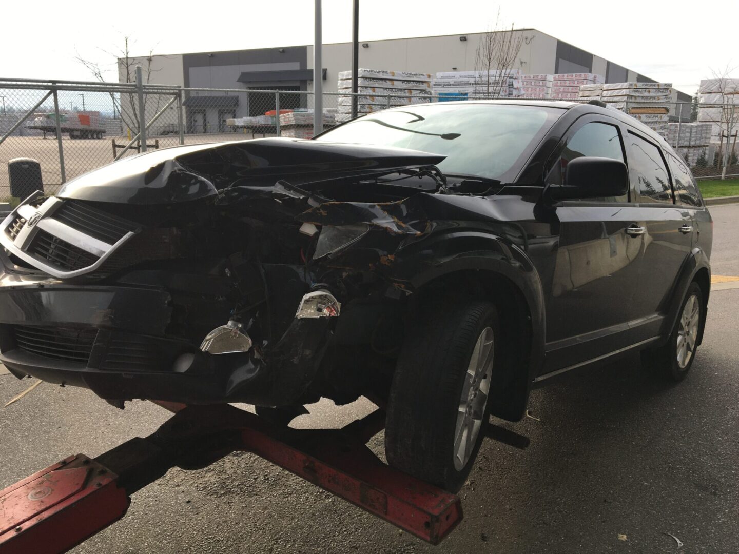 Black SUV with front-end damage mounted on a tow truck for scrap car removal.