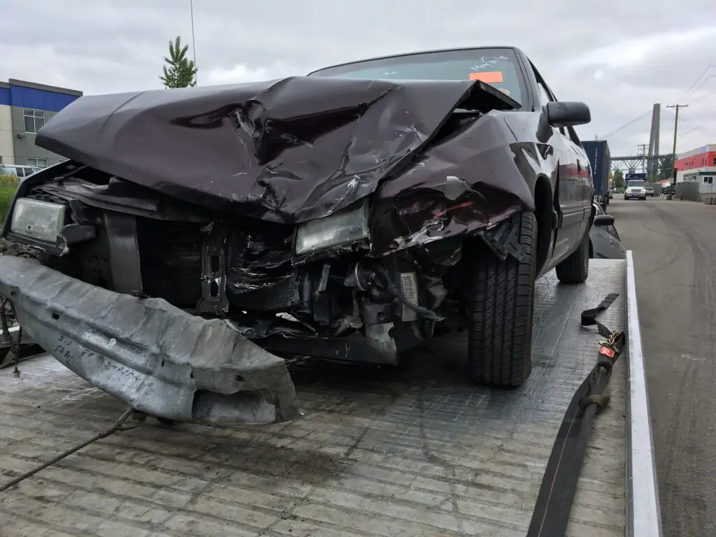 urn Your Accident Car into Cash in Vancouver BC! If you’re looking for Accident Car Buyers in Vancouver BC, you’ve come to the right place. damaged car with a crushed front end, awaiting scrap car removal, sitting on a tow truck.